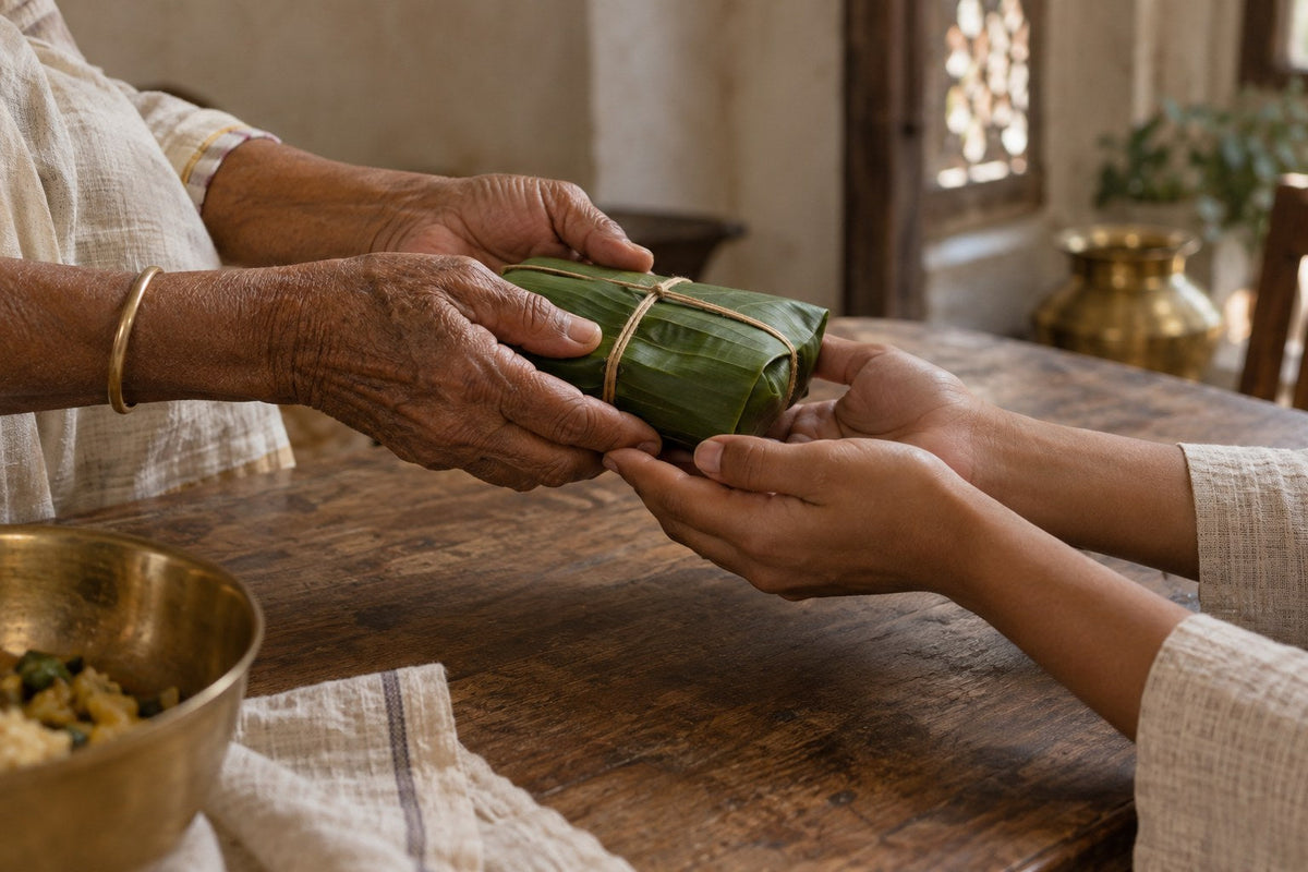 Older hands passing food wrapped in a banana leaf to younger hands