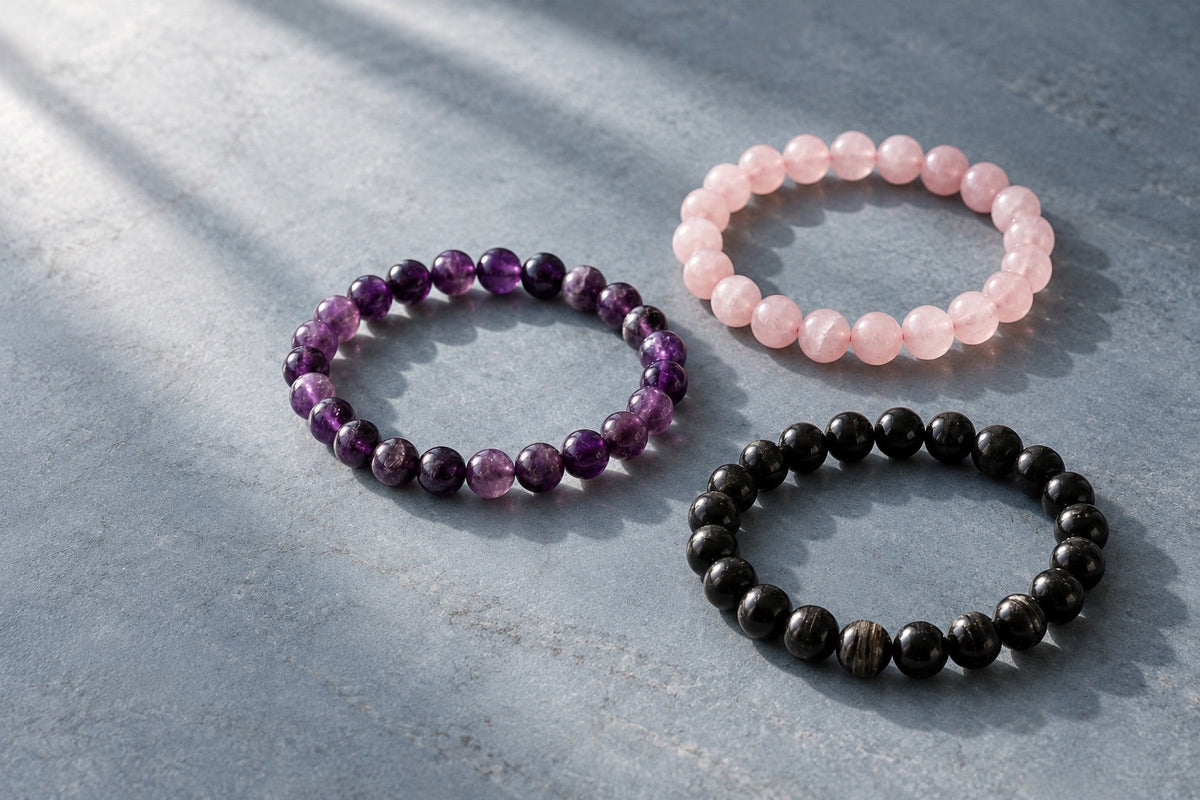 Amethyst, rose quartz and black tourmaline bracelets on grey stone