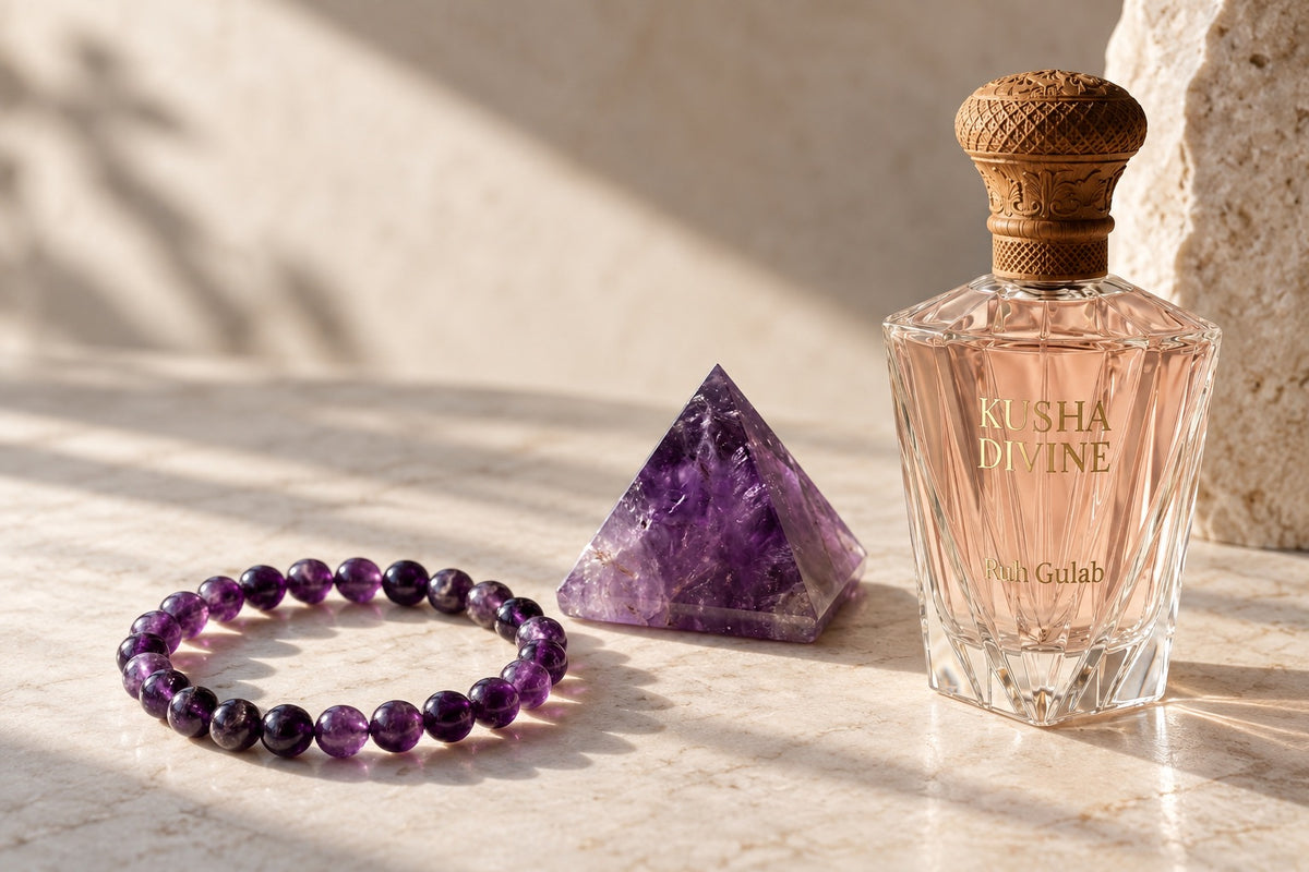 Amethyst bracelet, amethyst pyramid and a KUSHA DIVINE Ruh Gulab bottle on pale stone
