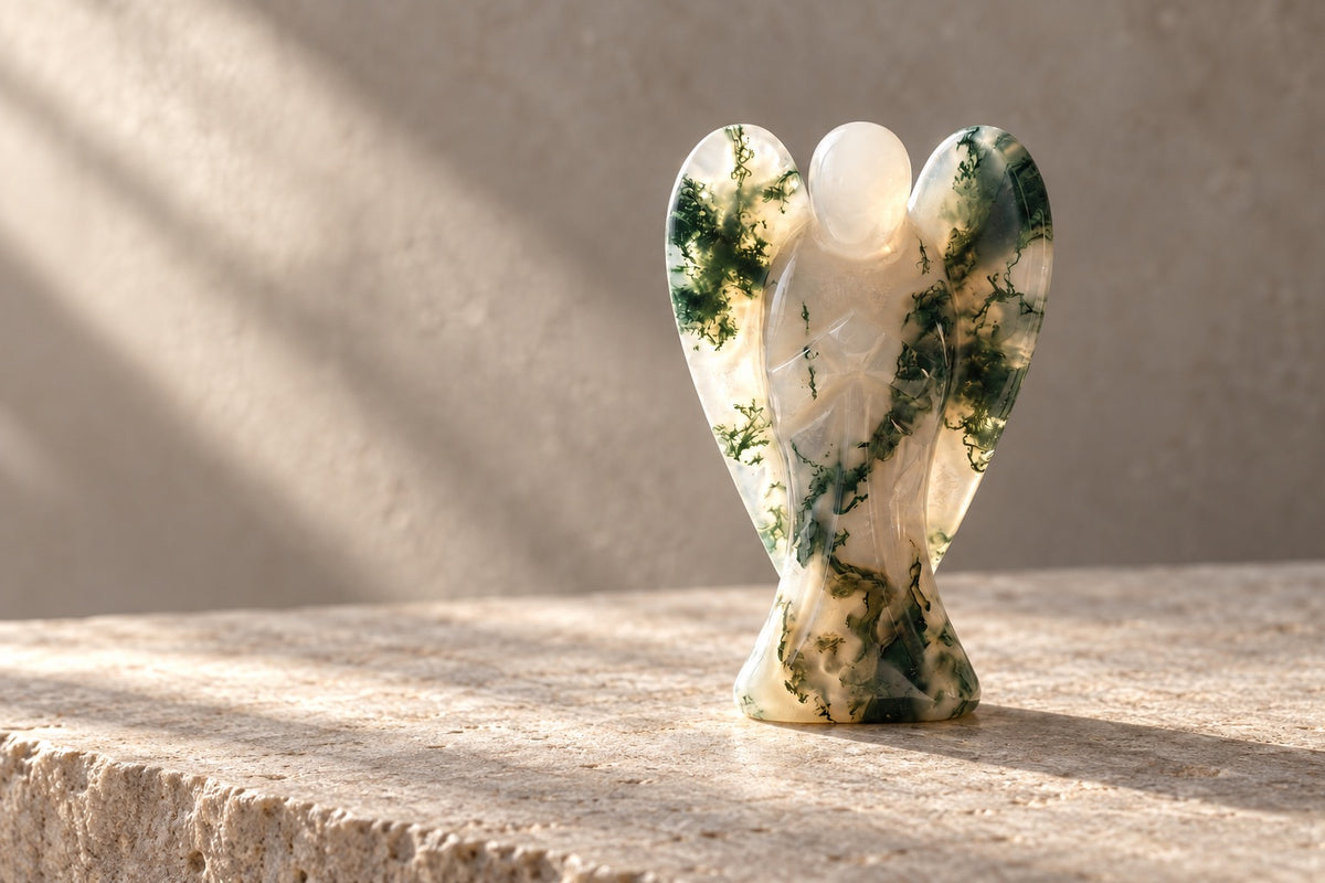 Moss agate angel figurine on a pale stone ledge