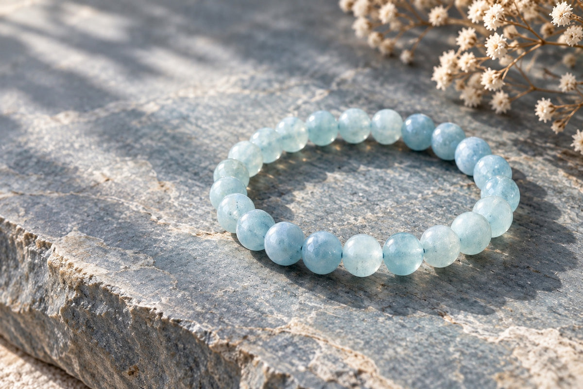 Pale blue aquamarine bracelet on grey stone beside dried flowers