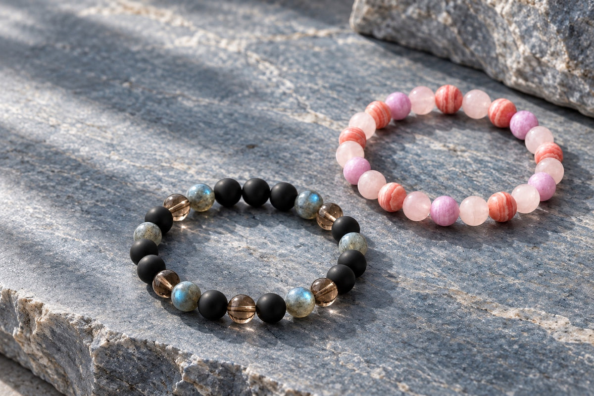 Two combination bracelets, one in black stones, one in rose and rhodochrosite, on grey stone
