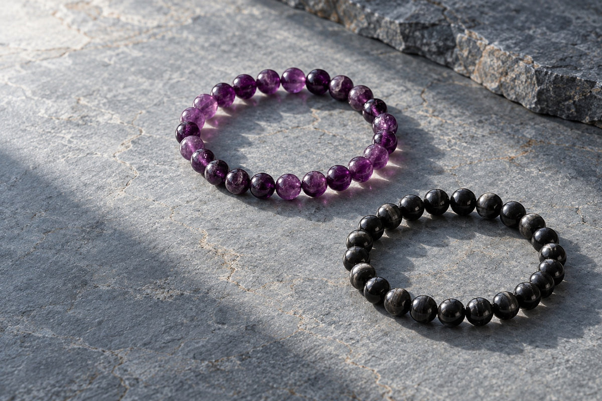 Amethyst and black tourmaline bracelets on grey stone