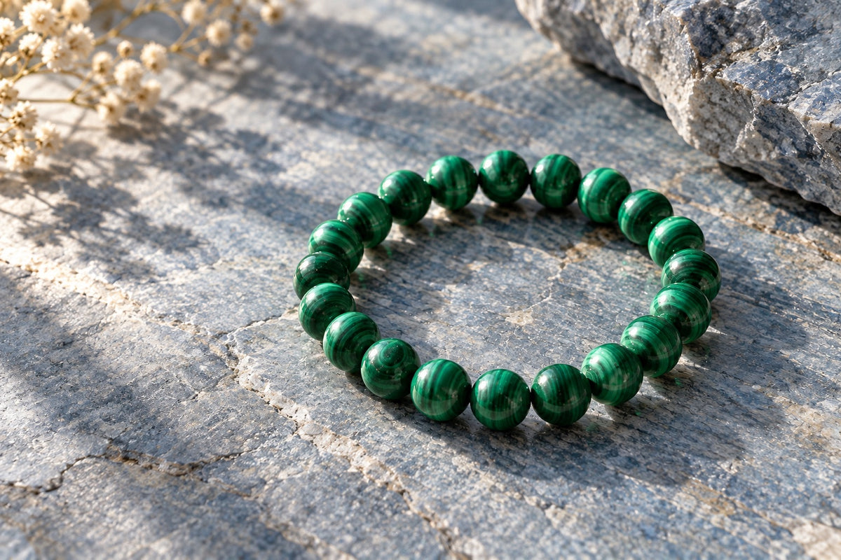Malachite bead bracelet on grey stone beside dried flowers