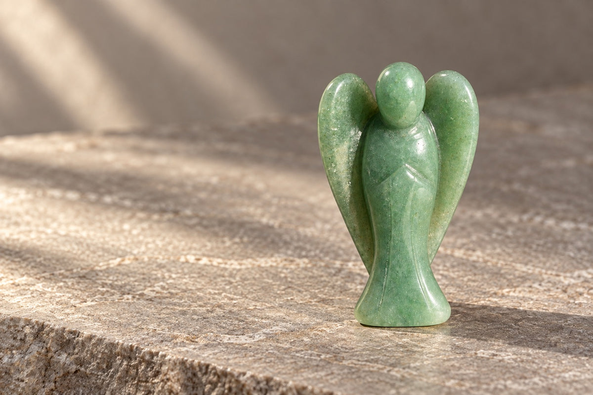 Small green aventurine angel figurine on pale stone